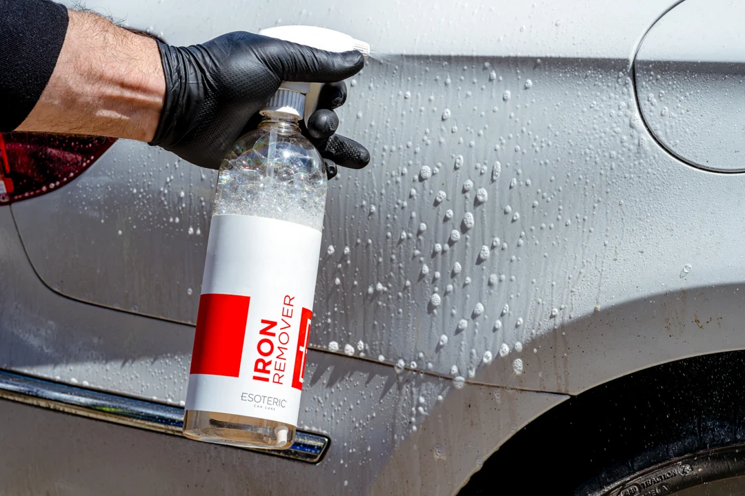 Detailer spraying iron-fallout remover on a car panel